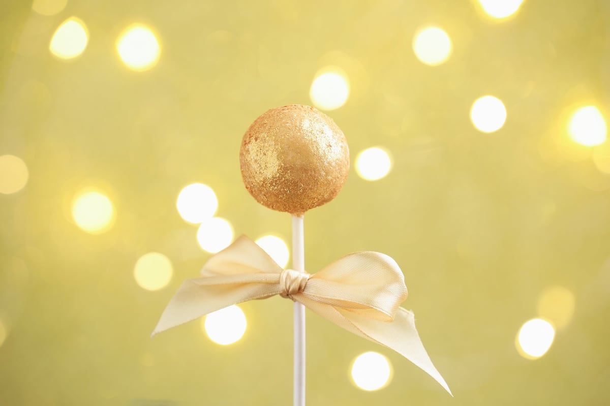 Tasty cake pop on beige background with blurred lights